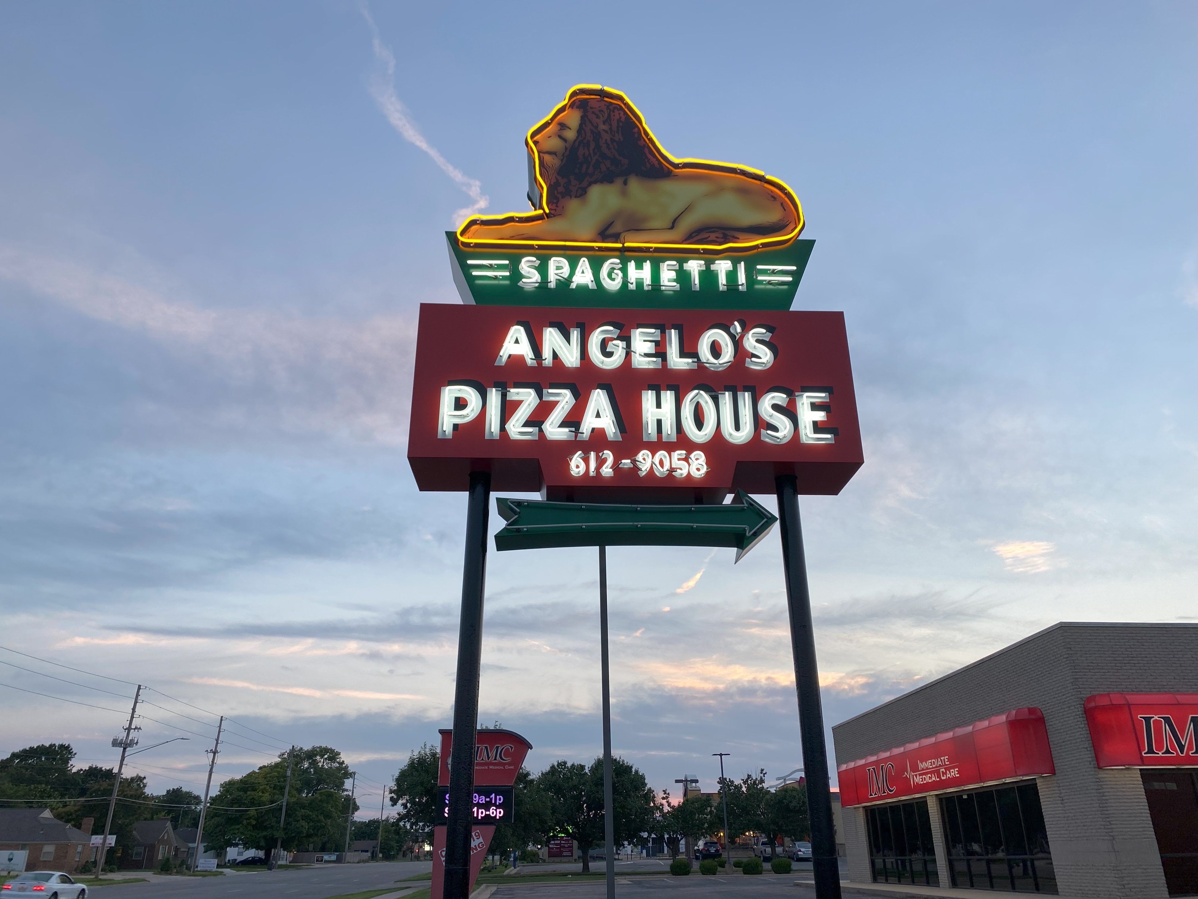 A neon sign for Angelo’s Pizza House, topped with a lion.