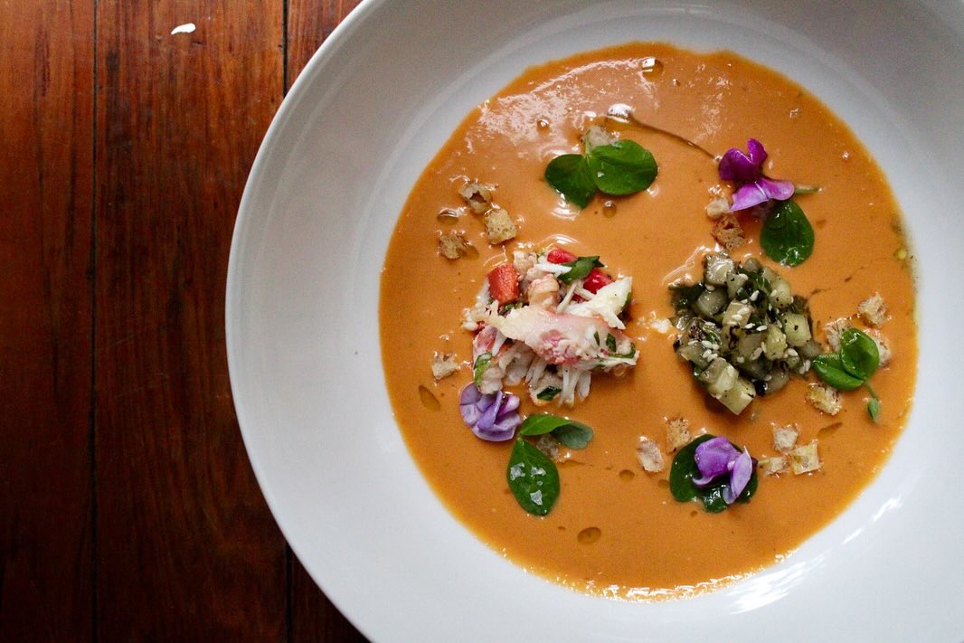 A soup garnished with flowers and crab meat.